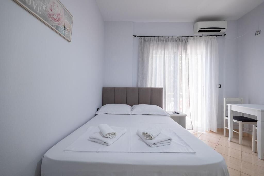 Una habitación de hotel con una cama, una mesita de noche, un escritorio y un equipo de aire acondicionado.
