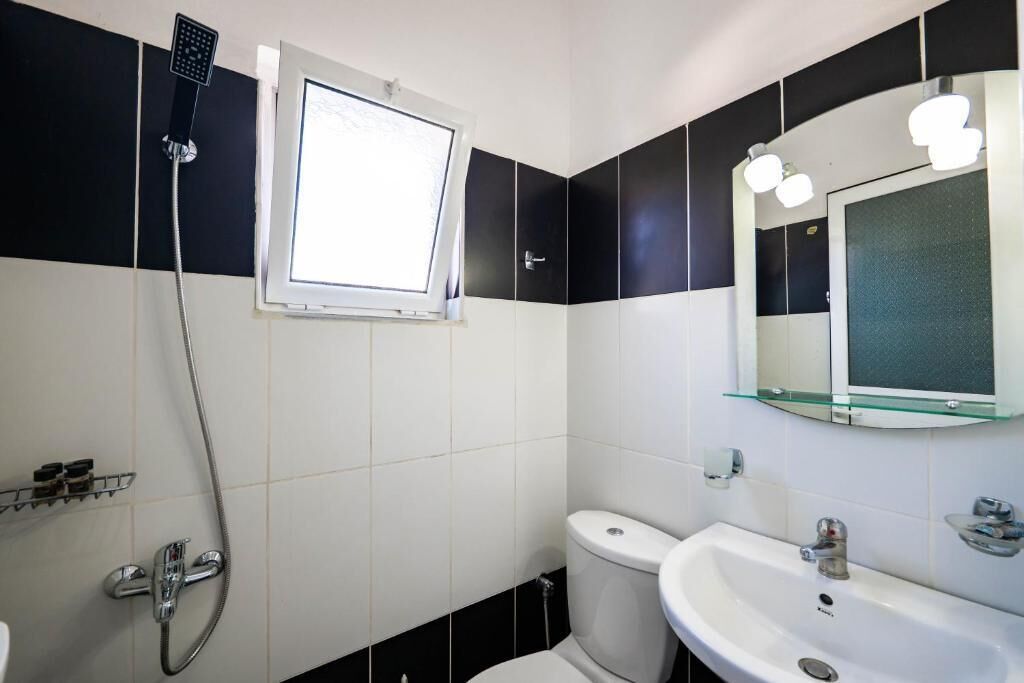 Une salle de bain équipée d’une douche, de toilettes, d’un lavabo et d’un miroir avec éclairage.