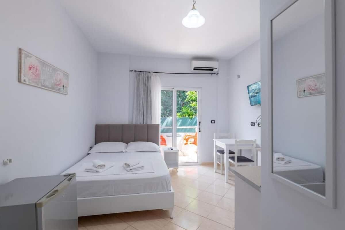 A modern hotel room with a bed, bedside table, chair, and a view of the outdoors.