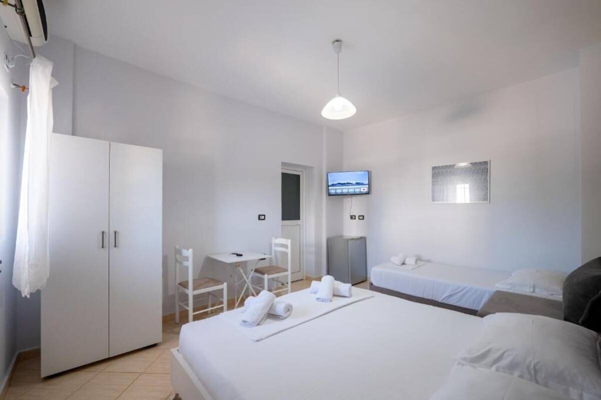 A hotel room with a bed, a desk, a chair, a TV, and a wardrobe.
