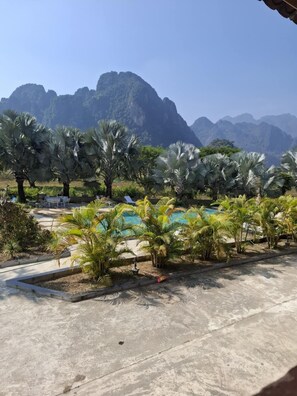A pool area with palm trees and mountains in the background. - VangVieng Elegance Boutique Resort (Vang Vieng)