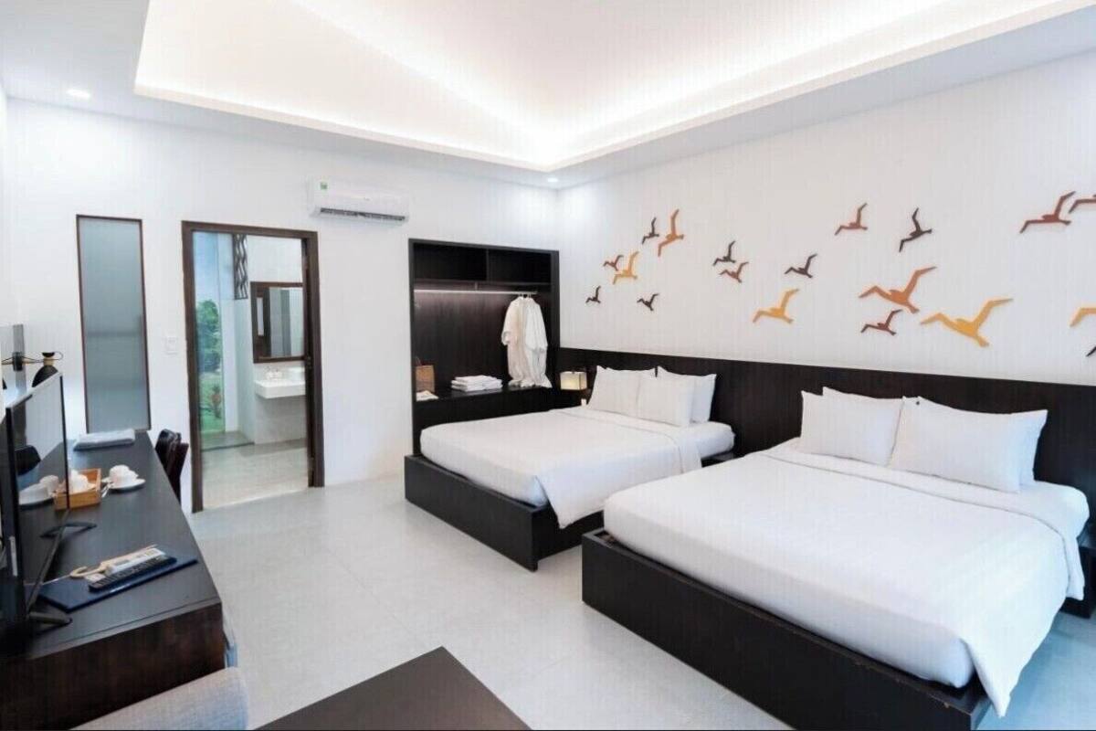 A modern hotel room with two beds, a desk, and a wardrobe.
