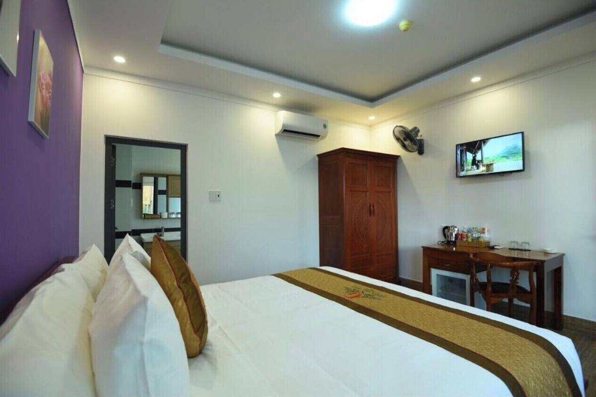 A hotel room with a bed, a desk, a TV, and a wardrobe.