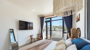 Ein Hotelzimmer mit Bett, Fernseher, Balkon mit Aussicht und einer Hängelampe.