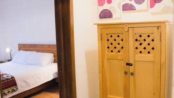 Une pièce avec une armoire en bois, un lit avec une literie blanche et un luminaire suspendu.