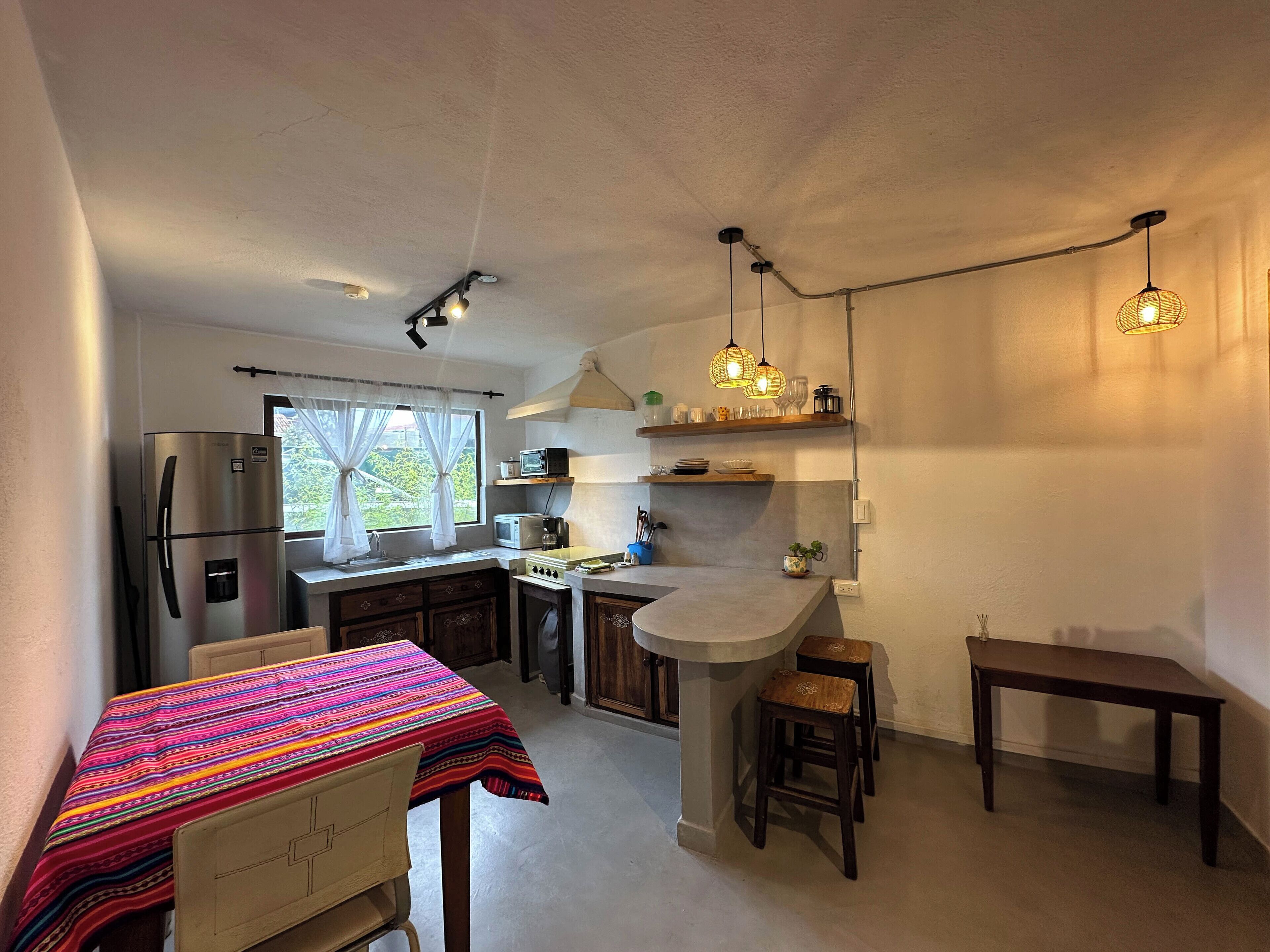 A compact kitchen with a refrigerator, microwave, stove, and a dining area with a table and chairs.