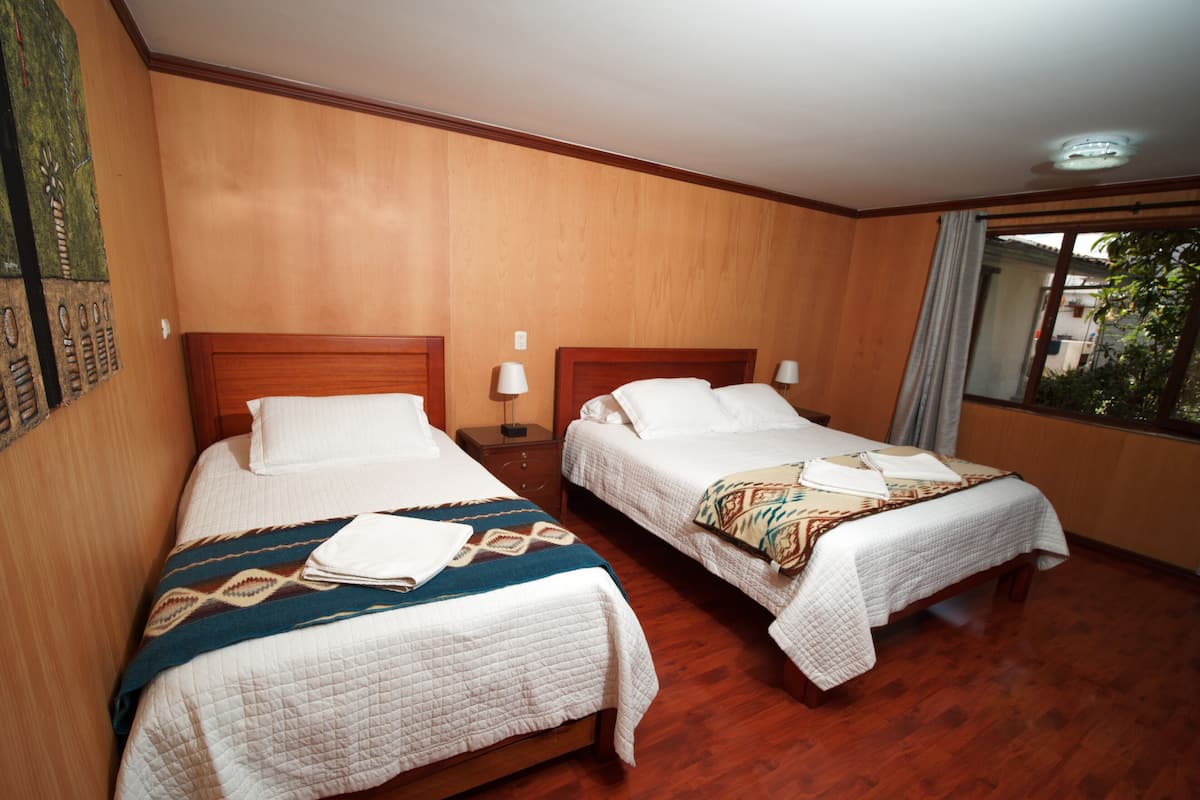 Habitación de hotel con dos camas, piso de madera y ventana con vistas.