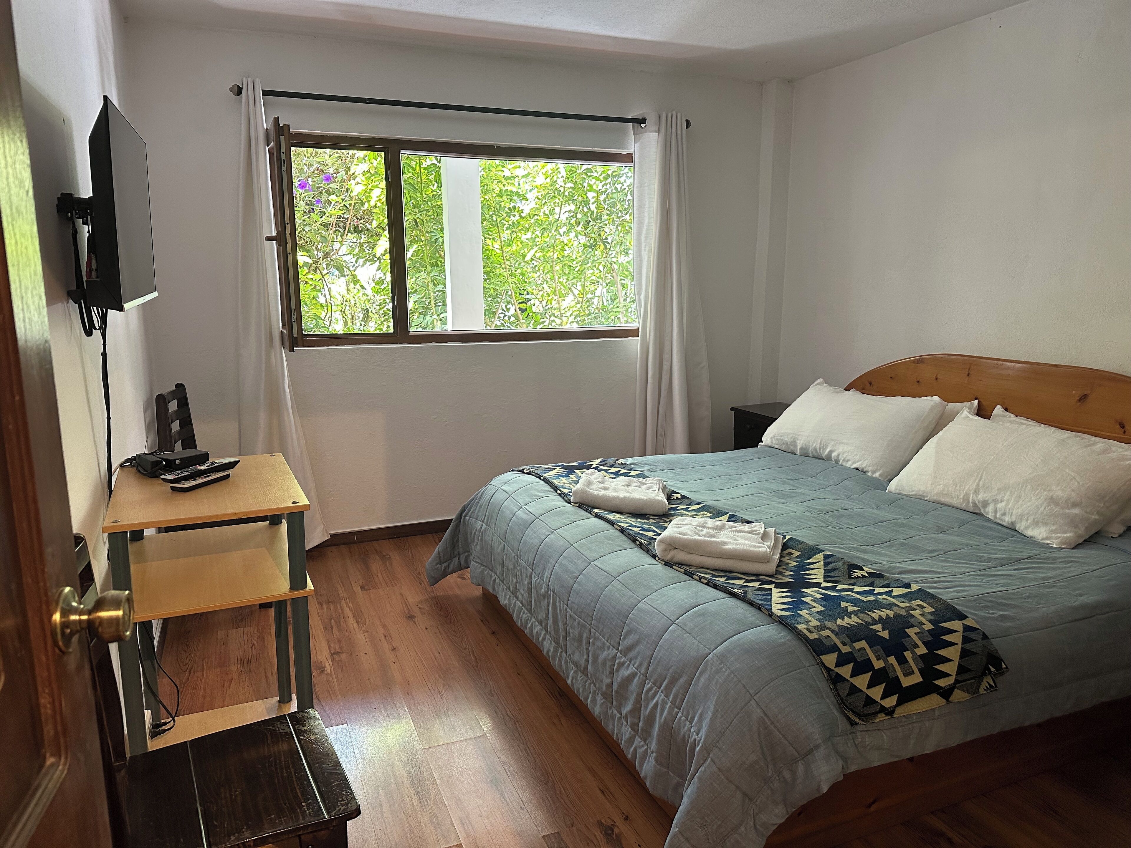 Ein Schlafzimmer mit Bett, Schreibtisch und einem Fenster mit Vorhängen.