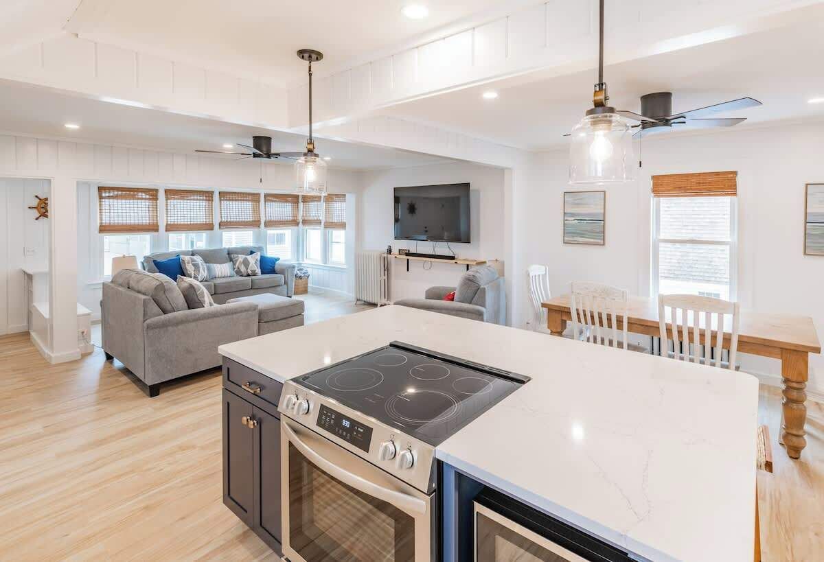 A modern kitchen with an island, built-in oven, and a dining area with a wooden table and chairs.