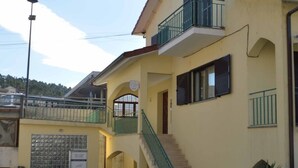 A two-story building with a balcony on the upper floor, a staircase leading to the upper level, and a sign on the ground floor. - Old Village Hostel (Ponte de Lima)
