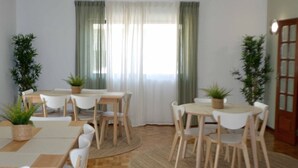 A dining area with two tables, white chairs, and potted plants. - Old Village Hostel (Ponte de Lima)