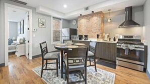 A modern kitchen with a brick accent wall, stainless steel appliances, and a dining area with a round table and chairs.