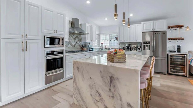 Una cocina moderna con armarios blancos, electrodomésticos de acero inoxidable y una isla de mármol.