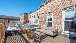 Terraço no topo com sofá, cadeiras e mesa de vidro.