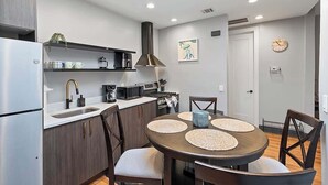 Cozinha moderna com ilha central, eletrodomésticos embutidos e área de jantar com mesa redonda e cadeiras.