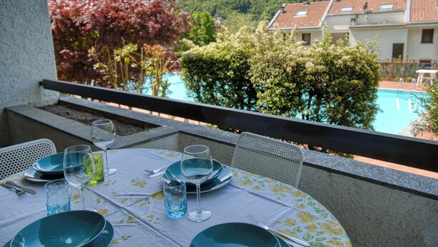 A table set for four with a view of a swimming pool and mountains in the background. - Top Panorama - Piscina (Introbio)