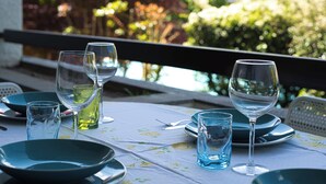 A table set with clear glasses and plates, a bottle of olive oil, and a floral tablecloth. - Top Panorama - Piscina (Introbio)