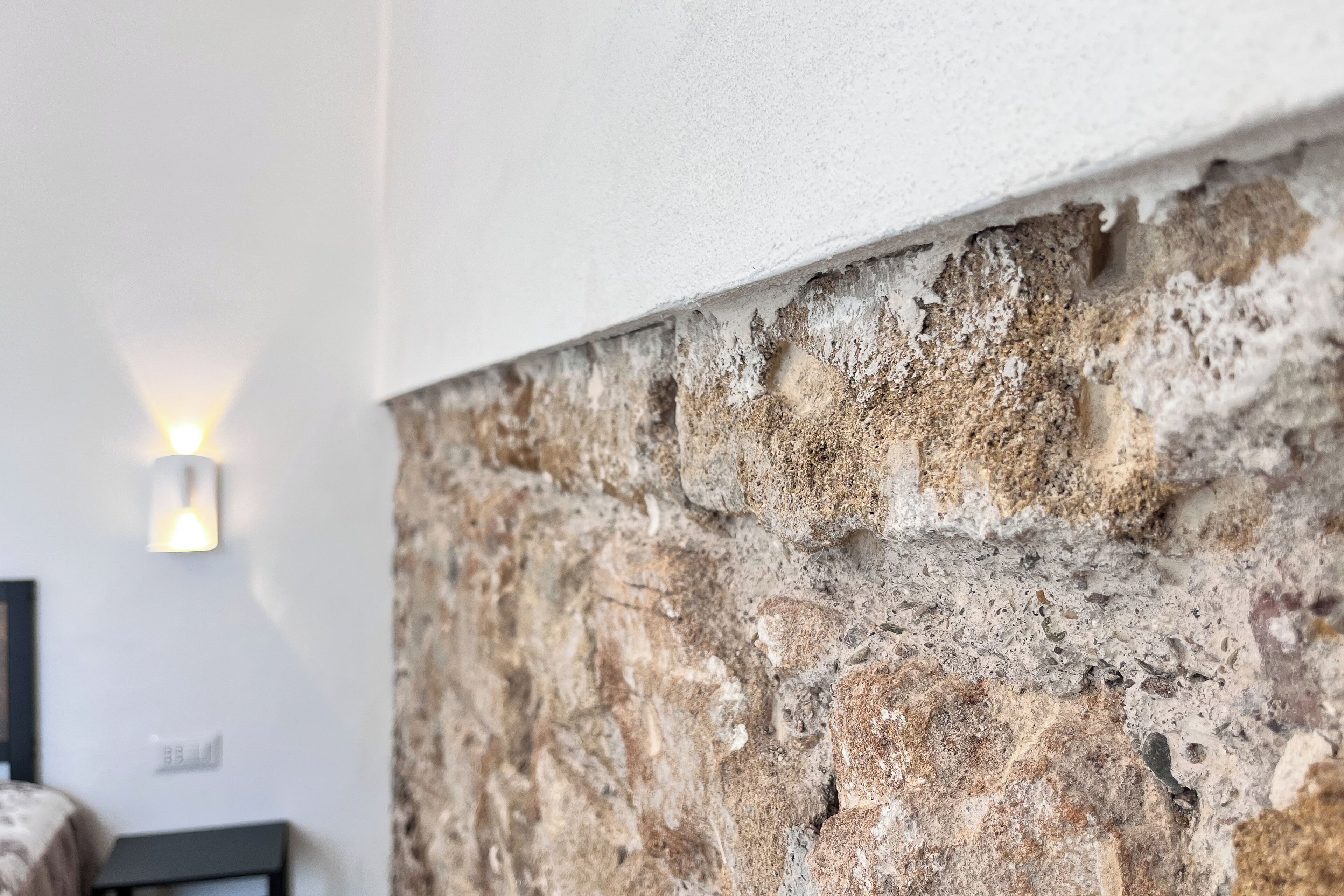 Een stenen muur met een structuur en een lamp bevestigd aan de muur.