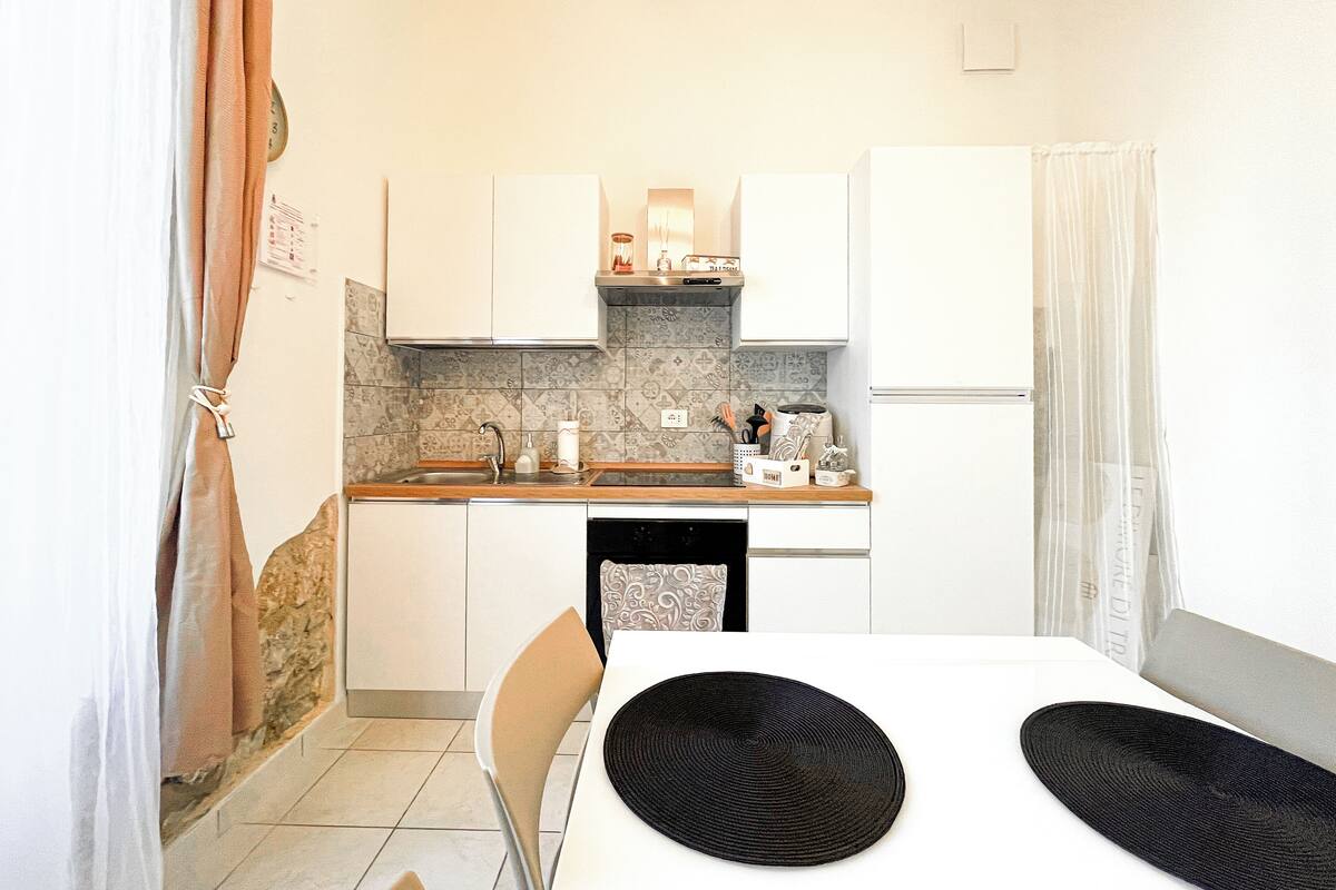 A compact kitchen with white cabinets, a tiled backsplash, and a small dining area with a table and chairs.