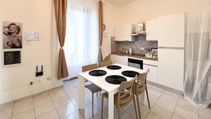 A modern kitchen with a dining table, chairs, and a refrigerator.