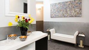 A modern bathroom with a white vanity, a mirror, a vase of yellow and red tulips, and a decorative wall art piece.