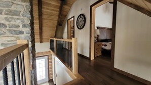 Een houten trap die leidt naar een slaapkamer met een bed en een nachtkastje.