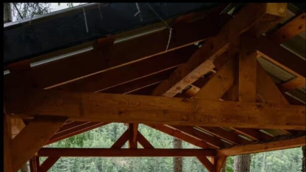 Een houten jacuzzi onder een pergola met uitzicht op een meer en bos.