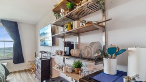 A modern kitchen with built-in shelves, a coffee machine, and a dining area with a bench. - ES326 Super Cute Village Studio Condo Slope View (Snowshoe)