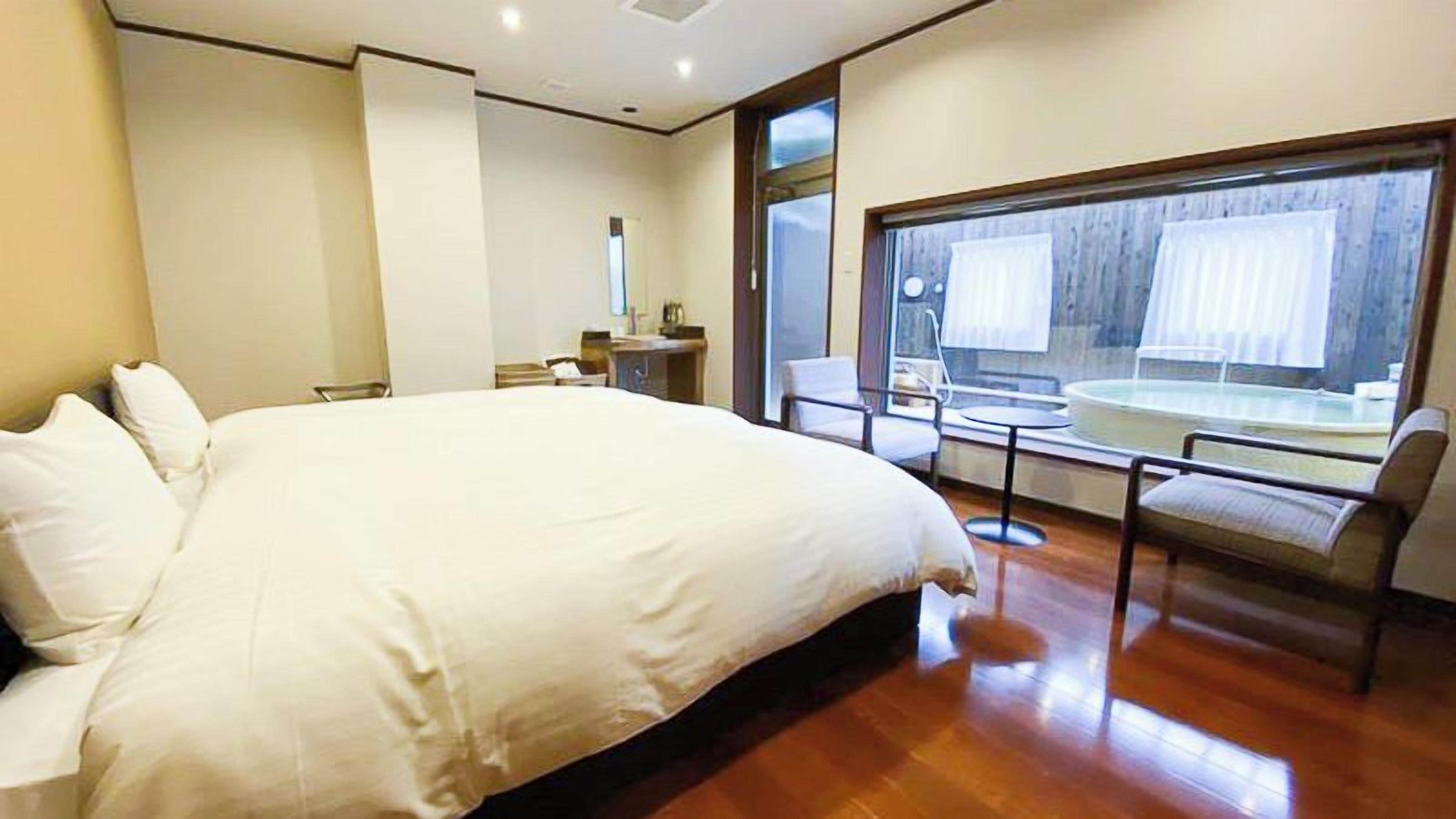 Una habitación de hotel moderna con una cama grande, un escritorio pequeño y un balcón con vistas.