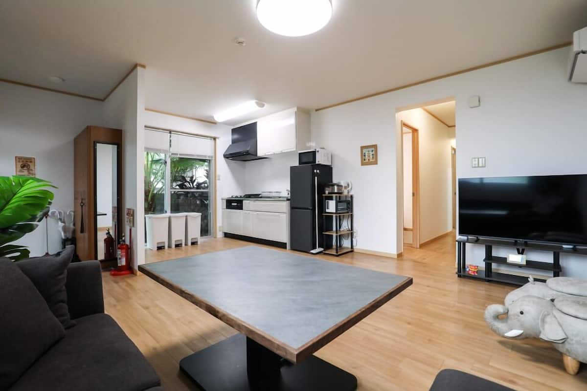 Ein modernes Wohnzimmer mit Esstisch, Sofa, Küchenbereich und einem Flachbildfernseher.