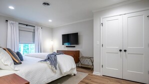 A bedroom with a bed, a TV mounted on the wall, a wardrobe, and a window with curtains. - The Square Unit 2, Cozy 1 BR by VelvetDitchVillas (Oxford)