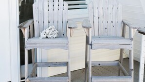 Two wooden Adirondack chairs on a wooden deck with a white railing and a staircase leading to an upper level. - A-Frame - 2 minute walk to Beach - Pet Friendly - HUGE front and back porch (Carolina Beach)