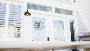 A white building with a large glass door labeled "THE BIG RAY". - A-Frame - 2 minute walk to Beach - Pet Friendly - HUGE front and back porch (Carolina Beach)