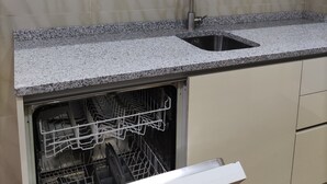 Une cuisine dotée d’un plan de travail en granit, d’un évier en acier inoxydable et d’un lave-vaisselle.