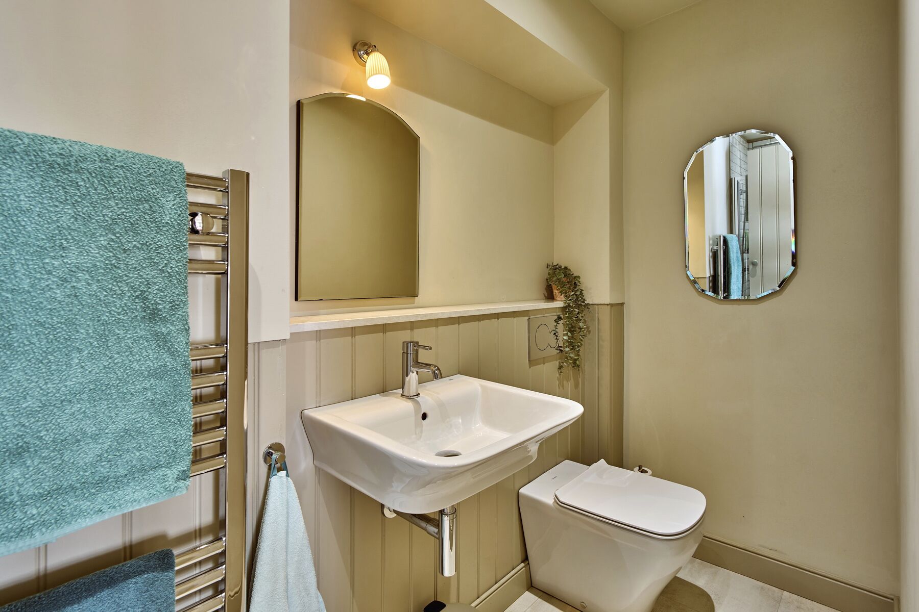 A bathroom with a white sink, a toilet, a mirror, and a towel rack.