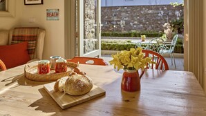 Un tavolo di legno con pane, un boccale di marmellata e un vaso di fiori.