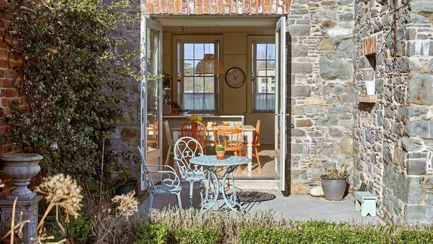 Un edificio in pietra con una porta di legno, una sala da pranzo con tavolo e sedie, e piante in vaso.