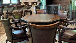 A dining area with a round table and six chairs, wooden walls, and a ship wheel decoration. - Family Fun! Diving Board/Water Slide/Boat Bar/ Beach/Jump Platforms/Green Lights (Eclectic)
