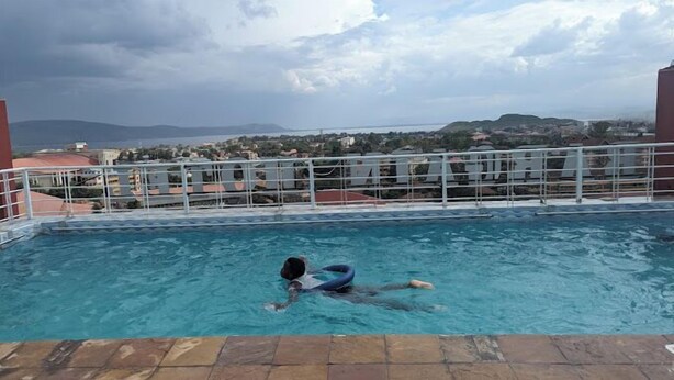 A swimming pool with a view of a town and mountains in the background. - Sweet Bargain Hotel (Nakuru)