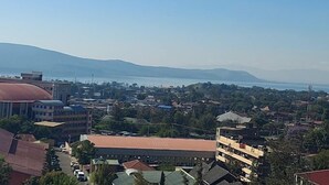 A cityscape with buildings, a body of water, and distant mountains. - Sweet Bargain Hotel (Nakuru)