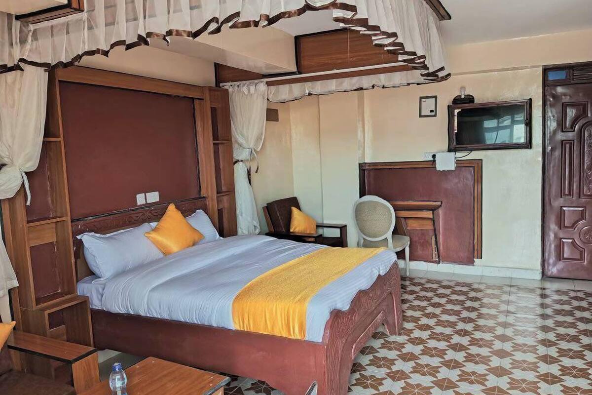 Habitación de hotel con una cama grande, un escritorio, una silla y un televisor.