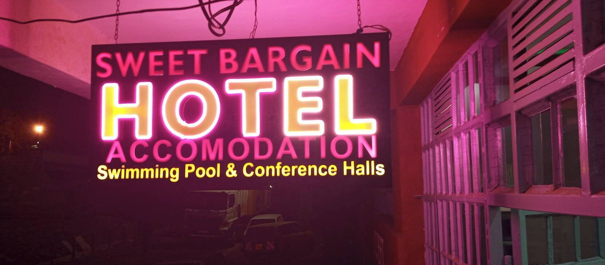 Letrero de neón del Hotel Sweet Bargain anunciando piscina y salones de conferencias.