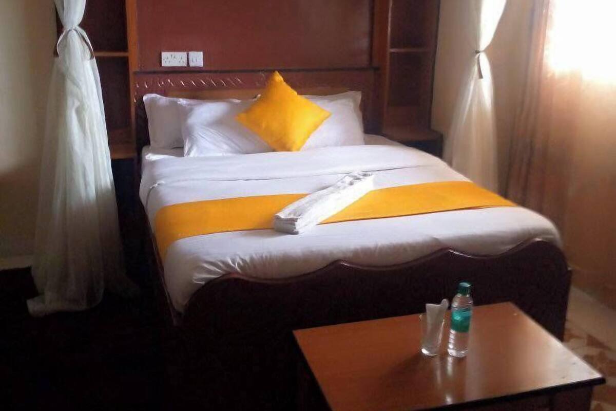 Una habitación de hotel con una cama, una mesita de noche y una ventana con cortinas.