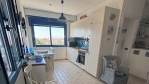 Une cuisine compacte avec un coin repas, une vue par la fenêtre et un petit coin salon agrémenté d’un tapis.