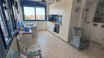 Een kleine keuken met een eethoek, uitzicht door het raam en een zithoek met vloerkleed.