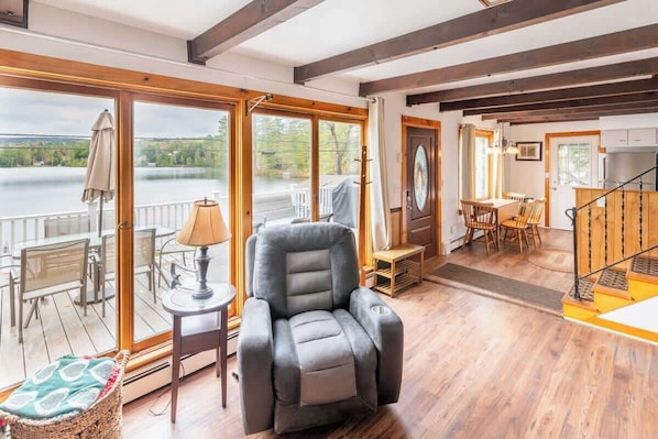 Una habitación con un ventanal grande, una silla reclinable, un comedor y una escalera.