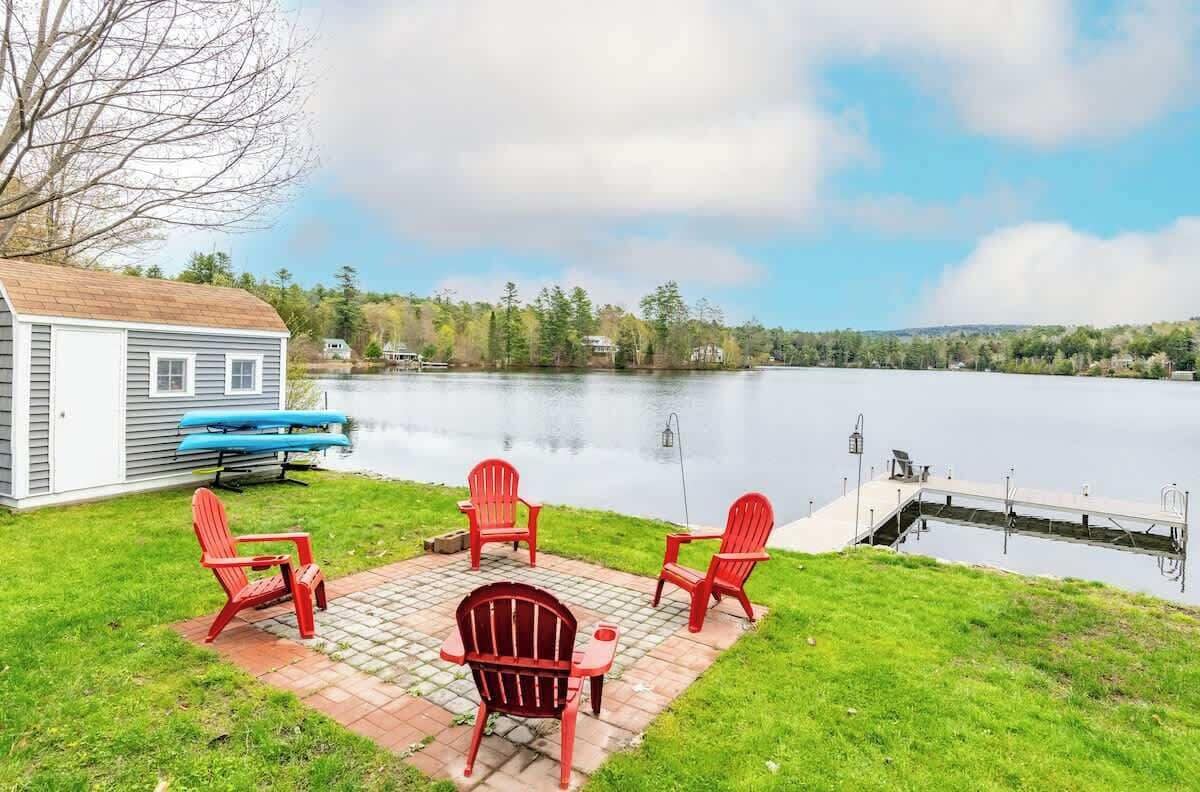 Un porxo al costat del llac amb cadires Adirondack vermelles, una caseta petita i un moll que s'endinsa a l'aigua.