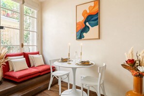 Un coin repas avec une table ronde, des chaises blanches et un canapé rouge.