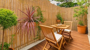 An outdoor patio area with a bamboo fence, wooden furniture, and potted plants. - 1538 Visconti (Paris)