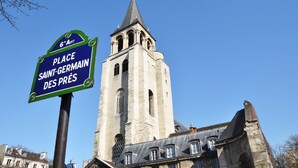 A historic church with a tall bell tower and a sign indicating 'Place Saint-Germain des Prés.' - 1538 Visconti (Paris)